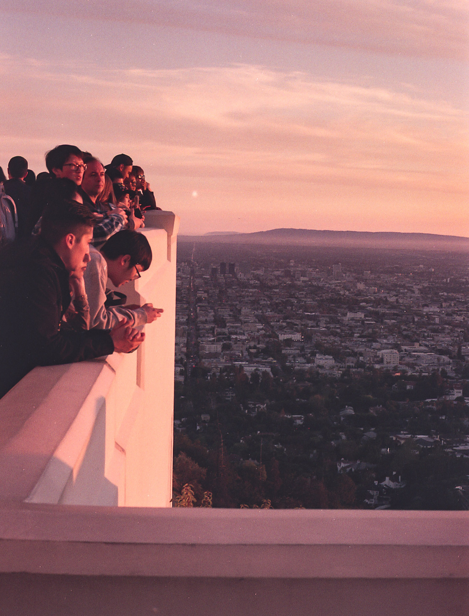 tourists looking out at los angeles during pink sunset at griffith observatory, 35mm film