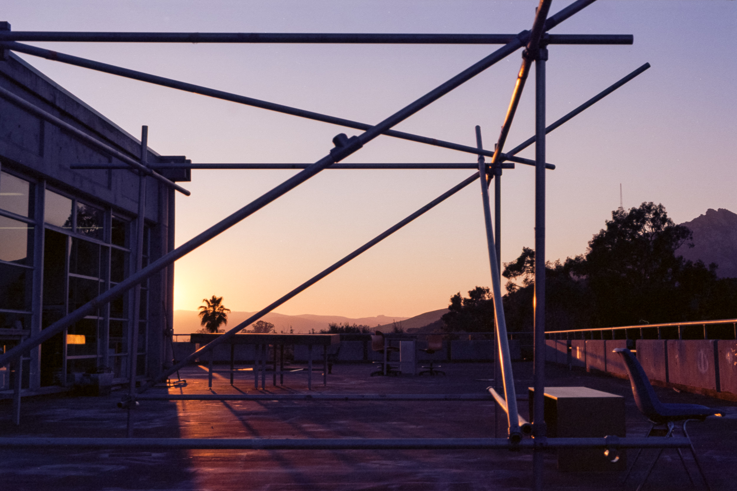 steel conduit structure with sloping members in front of bishop peak seen from cal poly architecture building at sunset, 35mm film