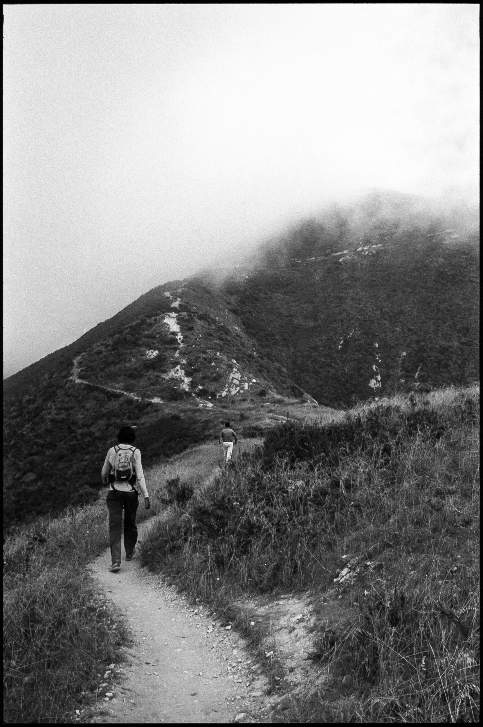 two men hiking a trail towards a foggy valencia peak in montana de oro state park california