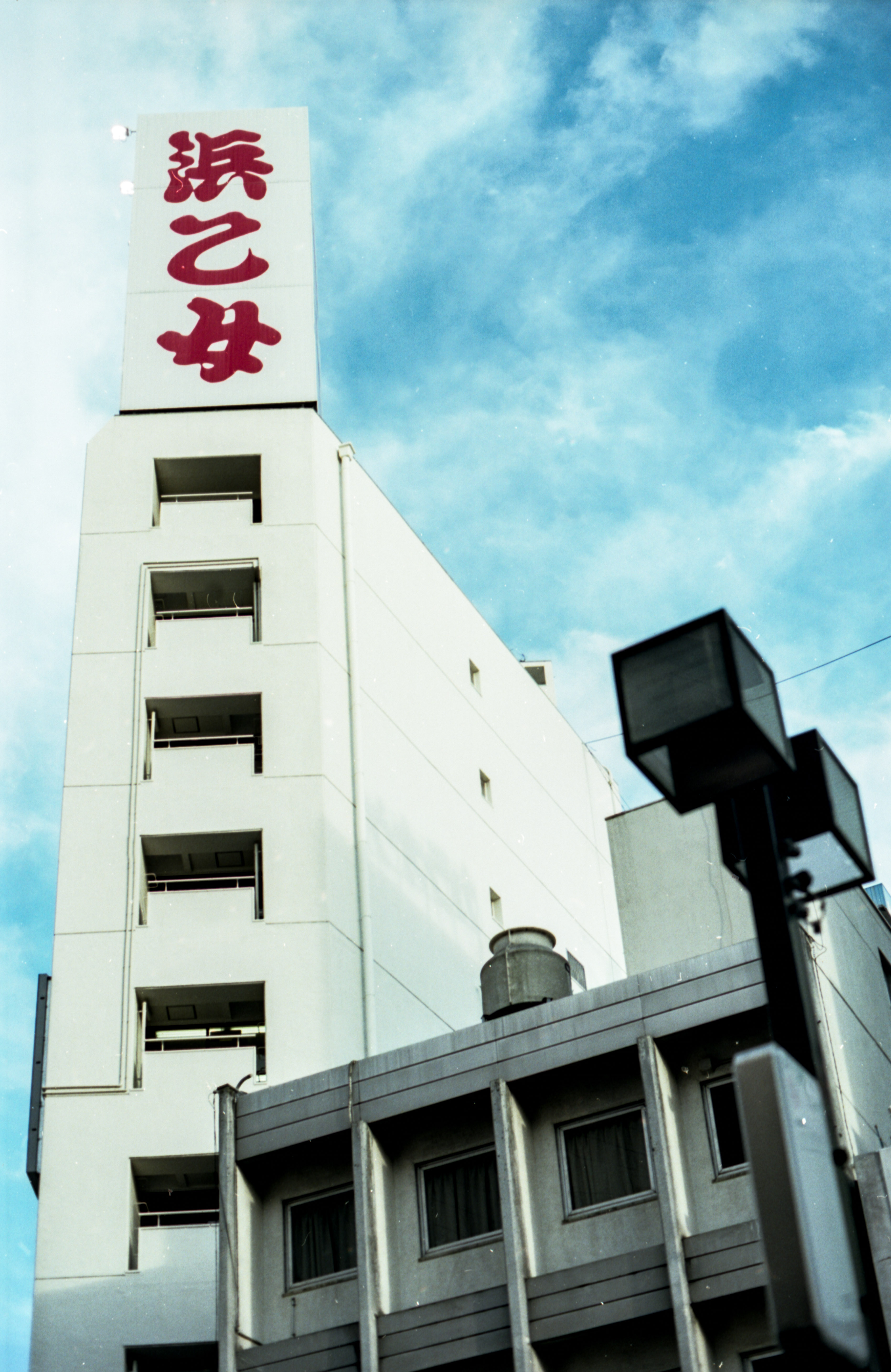 tall urban building with large red stylized kanji script on sign, 35mm film