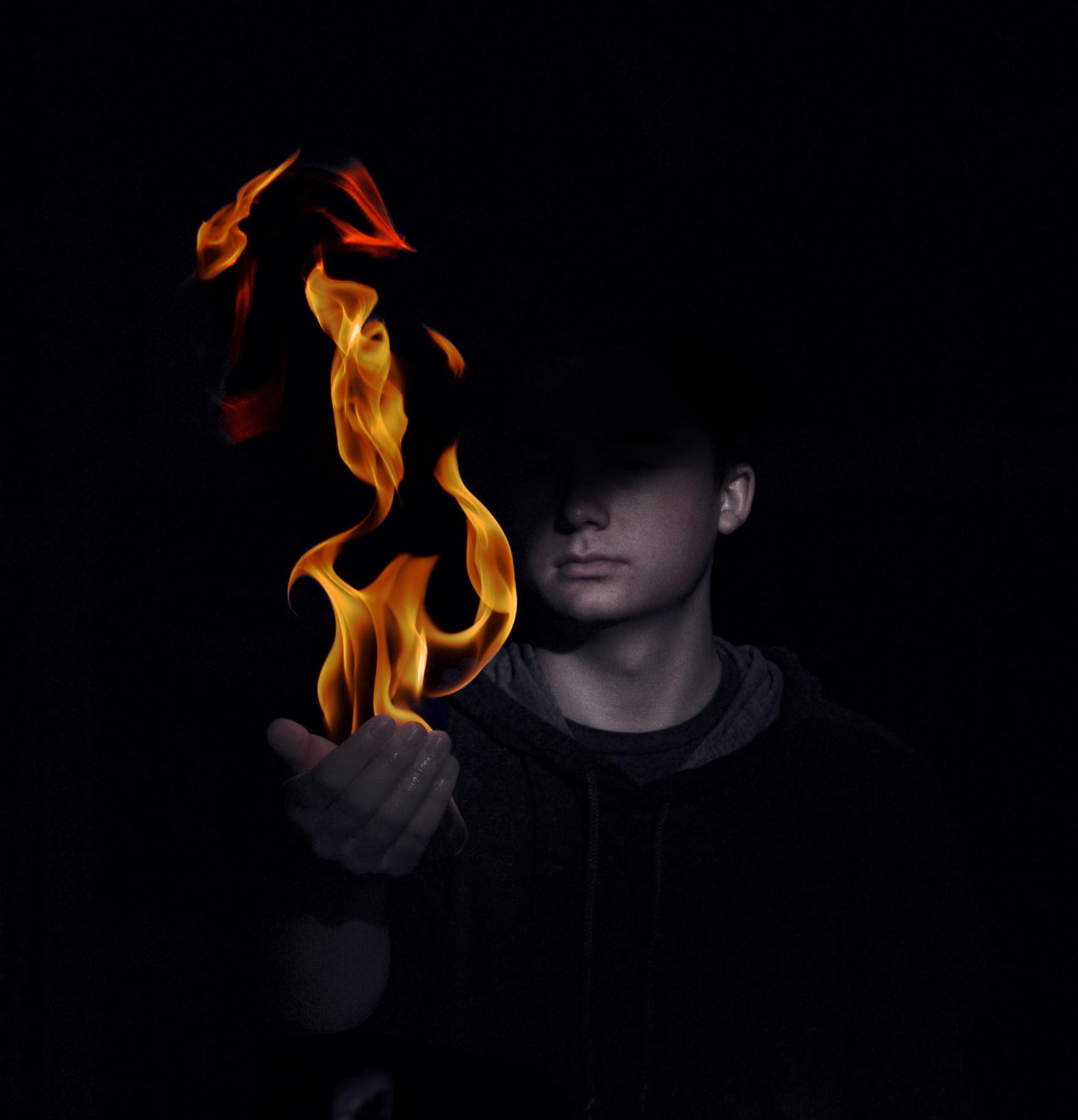 obscured, shadowy figure holds fire in hands