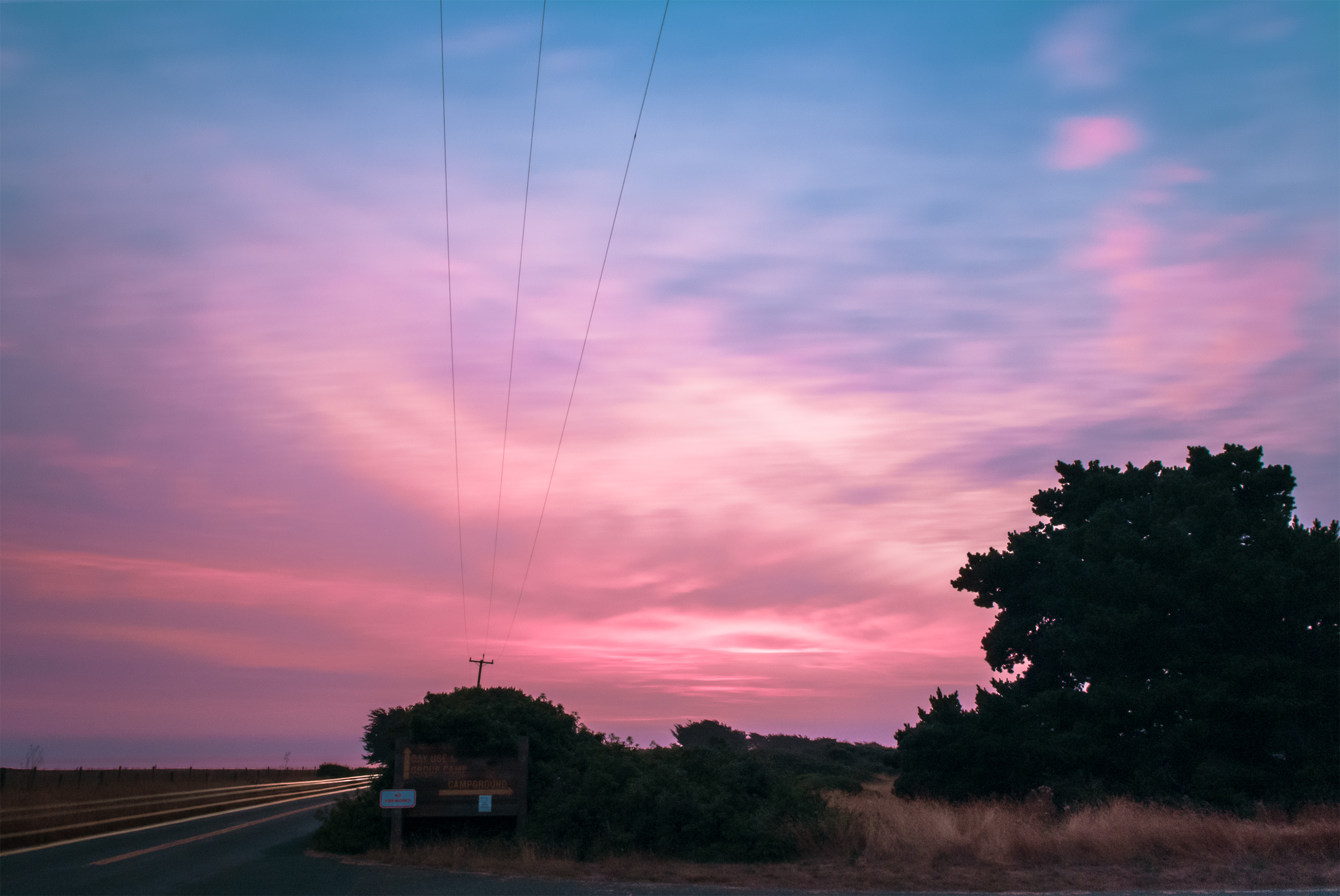 long exposure of blurred evening sky with streaked car lights in front of campground