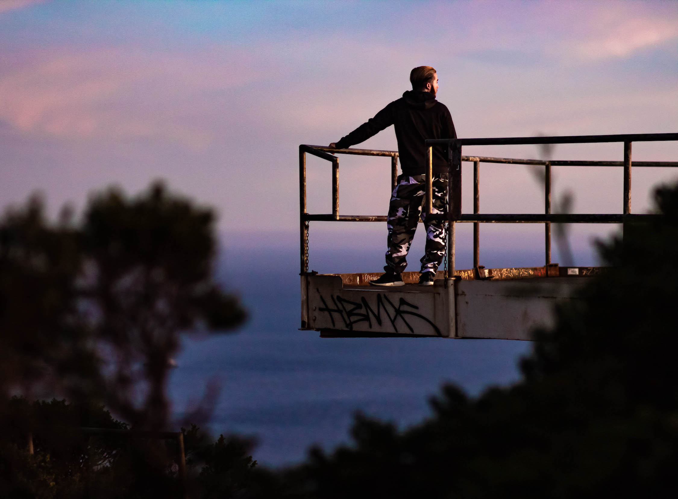 male figure poses on steel structure in front of san francisco bay at marin headlands, dusk
