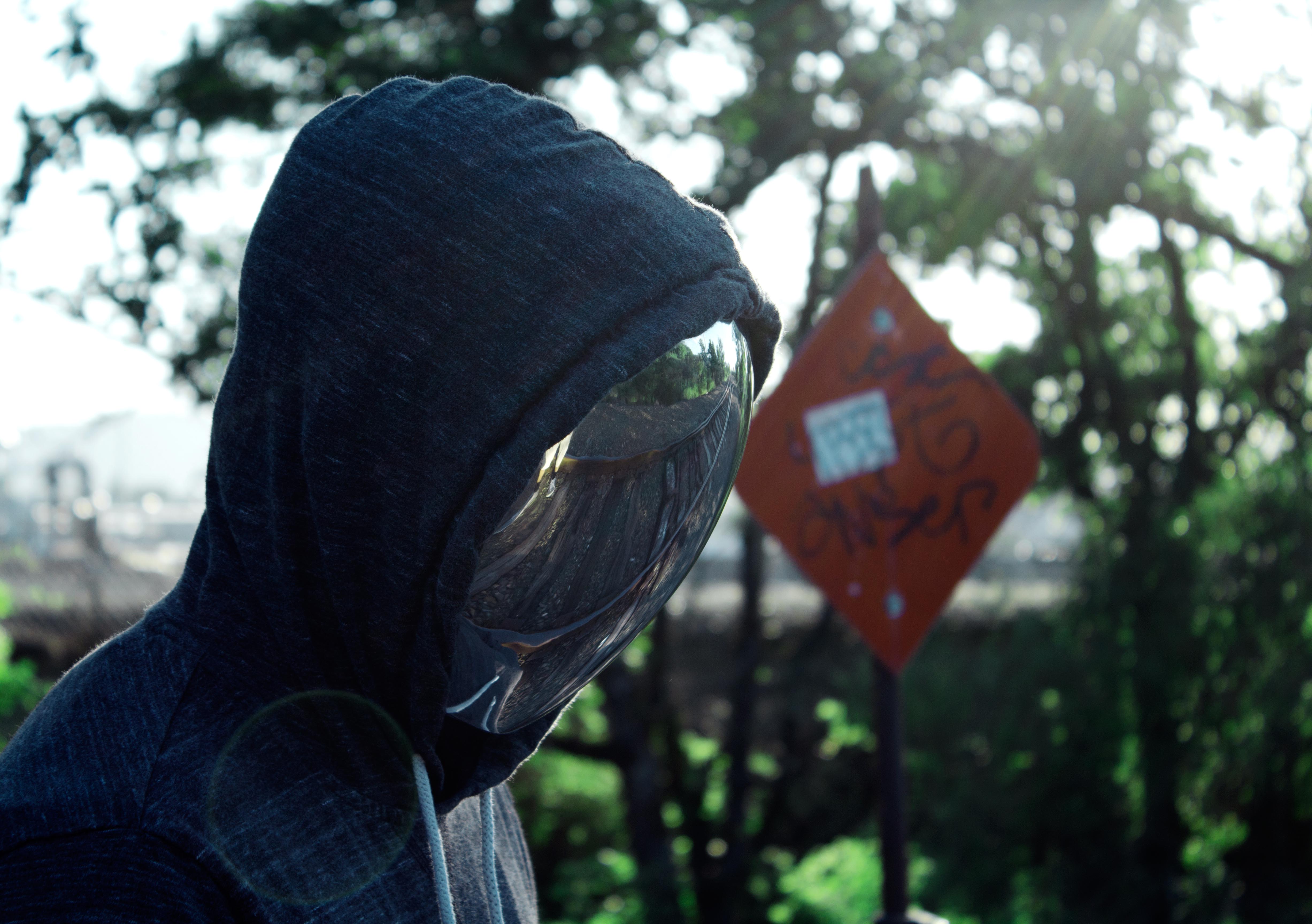 figure wearing mirror mask reflecting rural train tracks