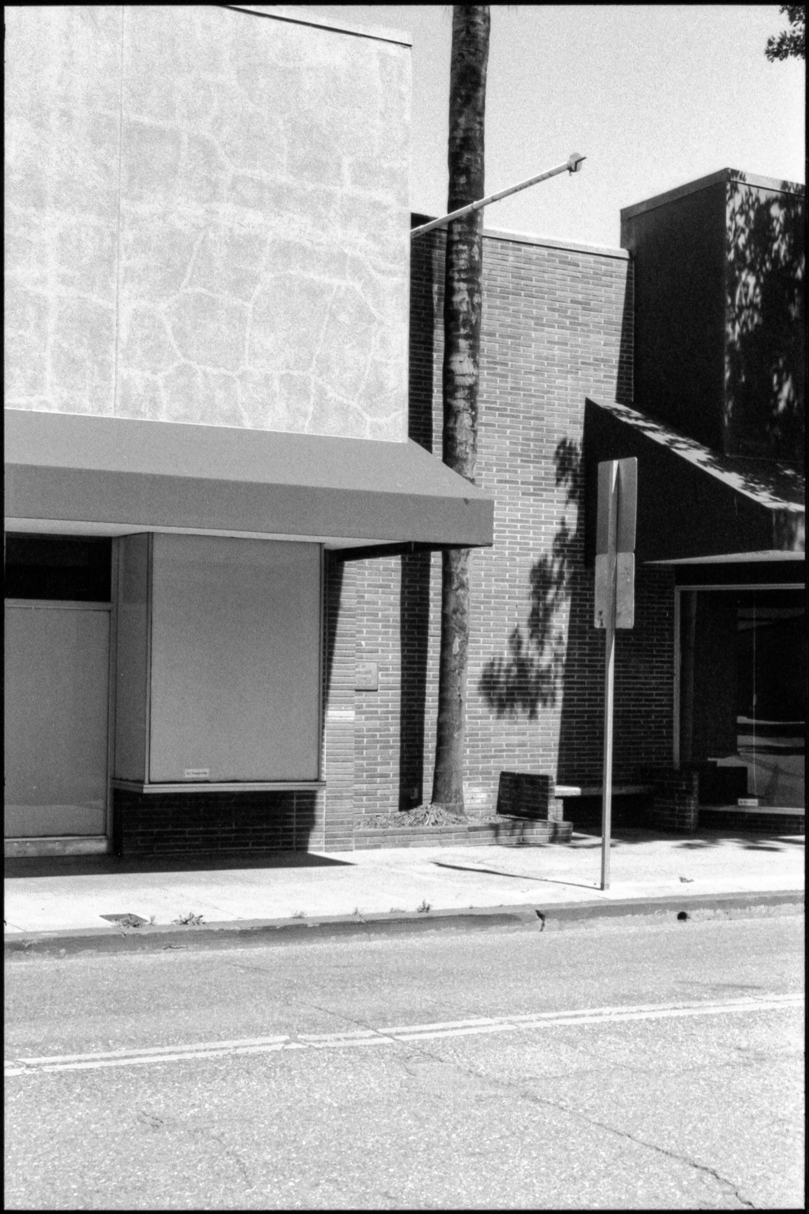 an empty shopfront on an empty sidewalk on a summer afternoon