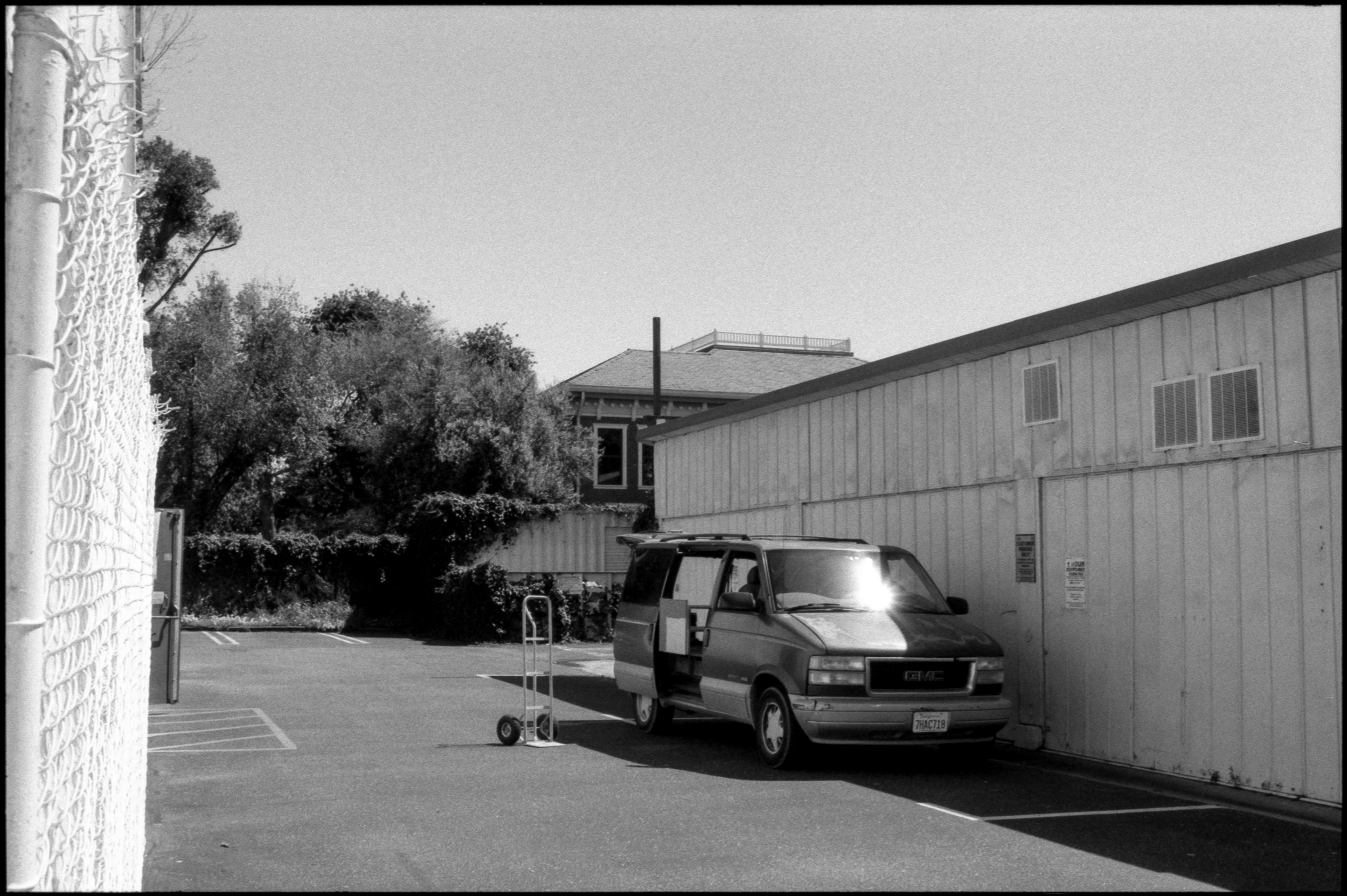 a gmc minivan with doors and hatchback open and an abandoned moving dolly next to it