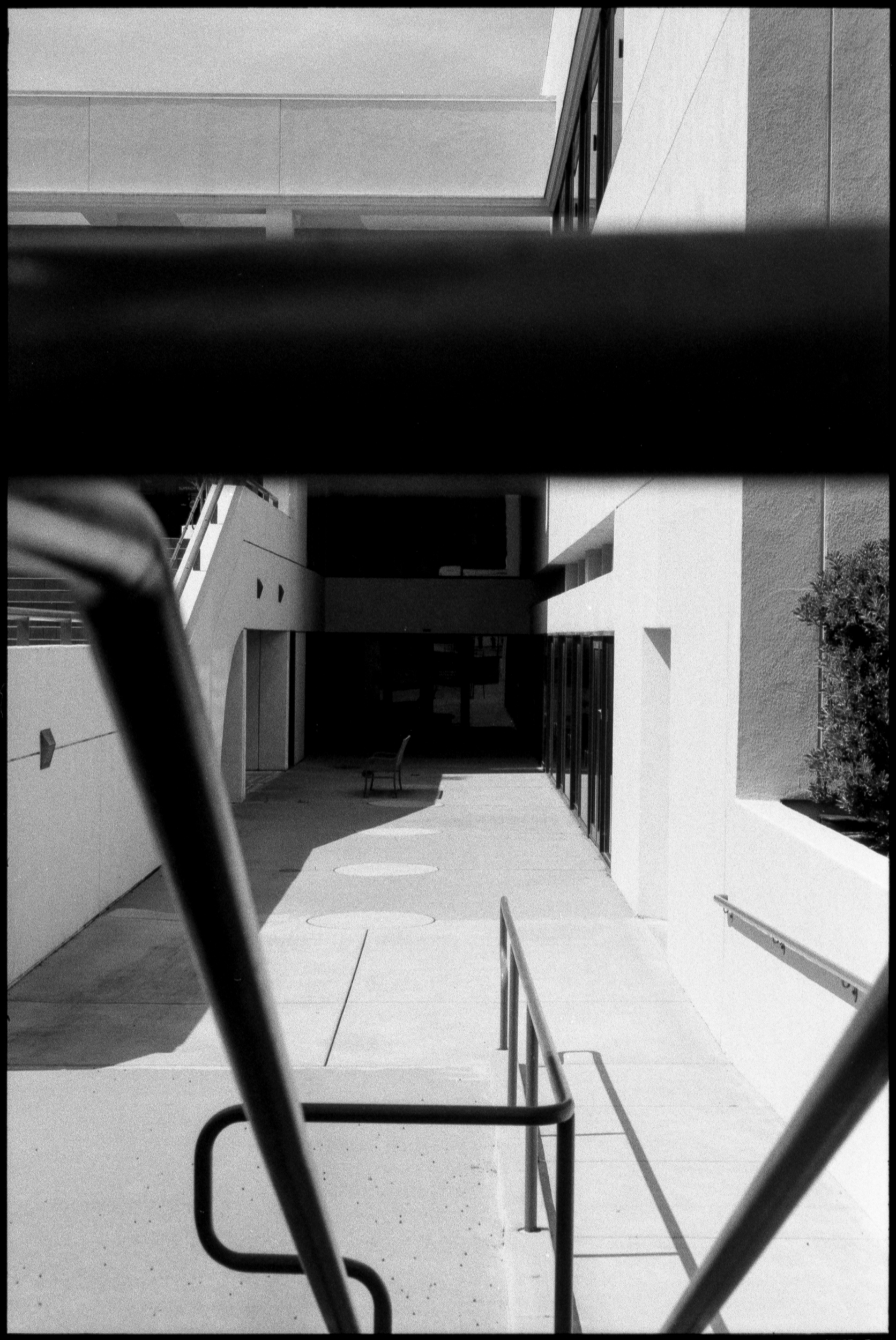 an empty chair sitting in the shadow of the san luis obispo courtroom, framed by guardrails
