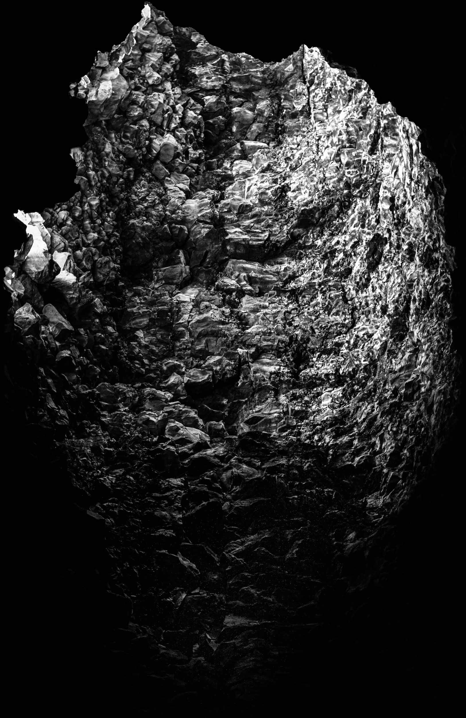 high contrast black and white abstracted photo of a large cave lit by distant sunlight