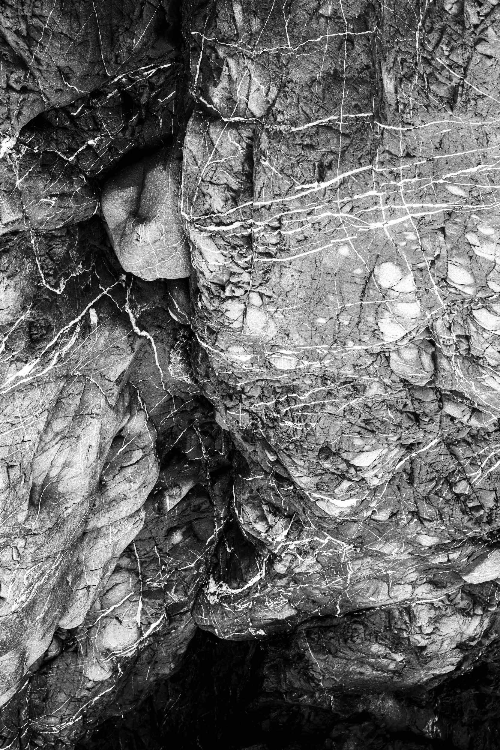 high contrast black and white photo of a bulbous igneous rock formation with veins of white embedded material