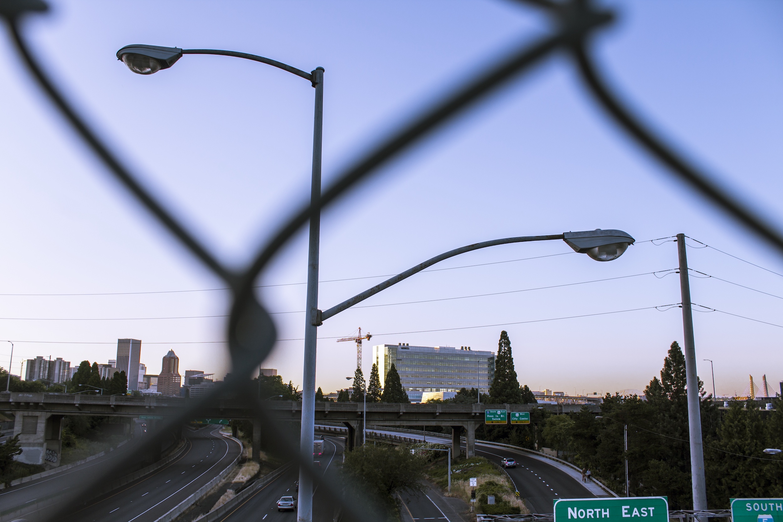 street lights through chain link fence above highway i-5 in portland oregon at twilight